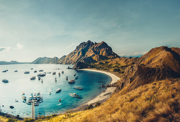 Mountains, ocean bay with boats. Aerial shot. Padar. Wonderful panoramic overview bay with the sand beaches surrounded by the mountains. Landscape of Padar island. Komodo National Park. Indonesia.