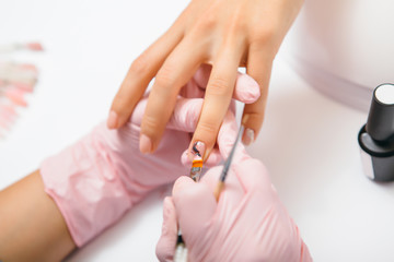 Manicure creation process. Closeup shot of a woman in a nail salon receiving a manicure by a beautician with nail file. Woman getting nail manicure. Beautician file nails to a customer.