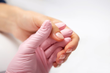 Manicure creation process. Closeup shot of a woman in a nail salon receiving a manicure by a beautician with nail file. Woman getting nail manicure. Beautician file nails to a customer.