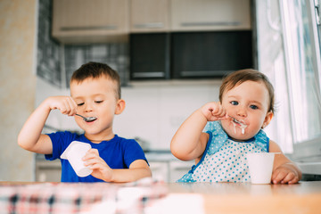 Boy and Girl in the kitchen eating yogurt on a warm summer day