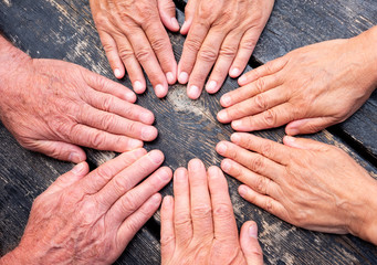 a group of hands touch to formalize their friendship. Caucasian people women and men. Dark wooden...