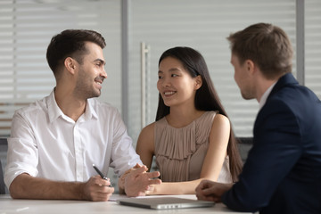Fototapeta na wymiar Smiling mixed ethnicity family couple talk consider mortgage loan offer