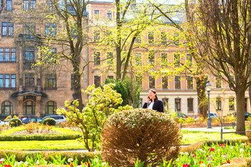 Lady speaks on the phone outside while walking in a city square