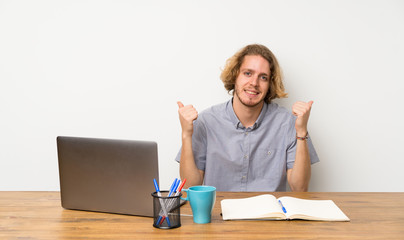 Blonde man with a laptop with thumbs up gesture and smiling