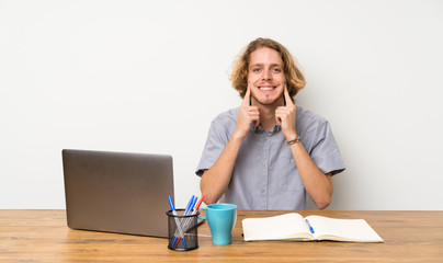 Blonde man with a laptop smiling with a happy and pleasant expression