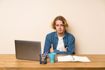 Blonde man with a laptop keeping arms crossed