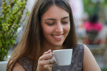 Portrait of a young beautiful woman sitting in a cafe outdoor drinking coffee	