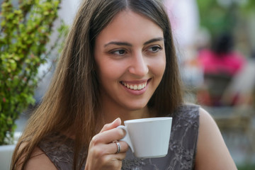 Portrait of a young beautiful woman sitting in a cafe outdoor drinking coffee	