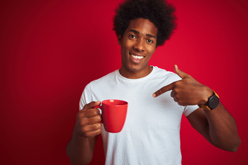 Young african american man drinking a cup of coffee standing over isolated red background with...