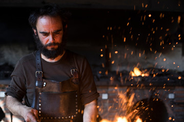 Adult blacksmith working in professional forge