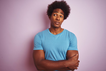 Fototapeta na wymiar African american man with afro hair wearing blue t-shirt standing over isolated pink background smiling looking to the side and staring away thinking.