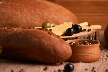 olive is on the table in background of bread, baguette and cheese. Selective focus