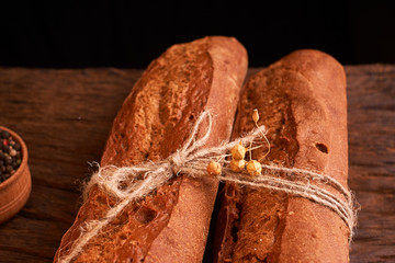 Two Fresh baguettes on dark wooden table. Selective focus