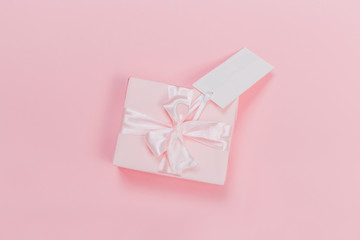 Gift box wrapped in pastel  paper with pink ribbon on pink surface. Top view  and  with copy space.