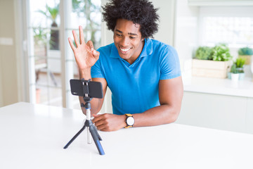 African American man doing online call with webcam using smartphone doing ok sign with fingers, excellent symbol