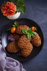 Delicious homemade beef burgers or cutlets (patties) with vegetables on black plate. overhead, horizontal