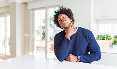 Fototapeta premium Young african american man wearing casual sweater sitting at home Touching painful neck, sore throat for flu, clod and infection