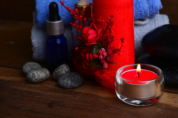 Red romantic candle and spa oil with towel and zen stone on wooden table