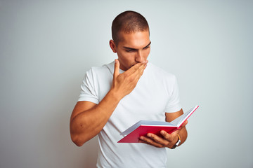 Young handsome man reading red book over white isolated background cover mouth with hand shocked with shame for mistake, expression of fear, scared in silence, secret concept