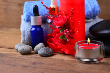 Red romantic candle and spa oil with towel and zen stone on wooden table