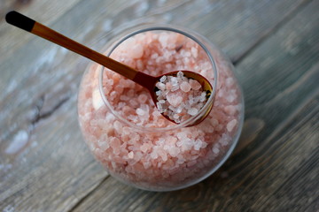 pink Himalayan salt heart-shaped figurine, salt crystals in a glass vase, love concept for Valentine's Day on February 14, on wooden background
