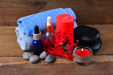 Obraz na płótnie Canvas Red romantic candle and spa oil with towel and zen stone on wooden table