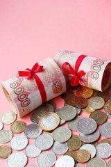 Russian money 5000 rubles twisted into a tube and tied with a ribbon, on a colored background, living coral the color of the year according to the version of Pantone