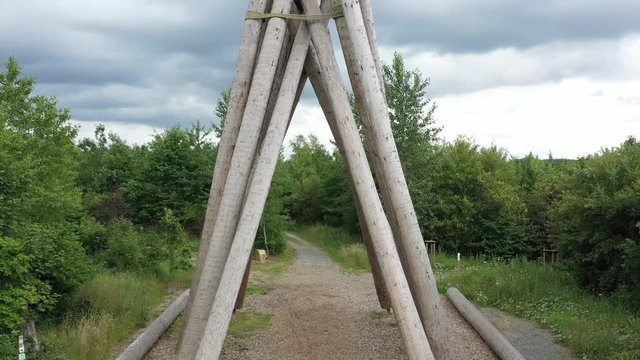 Several tree trunks form a triangle. They serve as a reminder of the storm Kyrill, who has uprooted many trees. Camera flight over the Kyrill gate at Brilon with a pan over Petersborn.