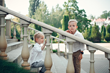 Two boys in a white shirt and trousers sit on steps