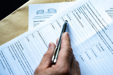 Writes legal documents to the European Court. Filing a complaint to a higher European court. A man writes a legal document with a pen.