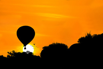 Silhouette of hot air balloon over sunset background