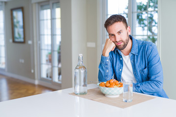 Handsome man eating pasta with meatballs and tomato sauce at home thinking looking tired and bored with depression problems with crossed arms.