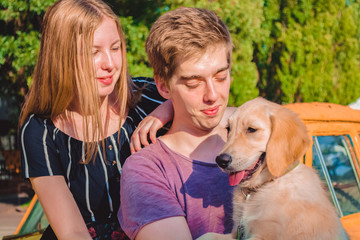 The young married loving couple walks with the little dog in the park. Golden retriever. 