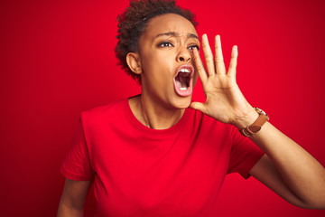 Young beautiful african american woman with afro hair over isolated red background shouting and screaming loud to side with hand on mouth. Communication concept.