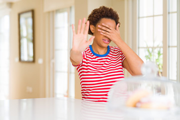 Young beautiful african american woman at home covering eyes with hands and doing stop gesture with sad and fear expression. Embarrassed and negative concept.