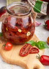 Sun dried tomatoes with herbs, garlic and olive oil in jar. Vegetarian food.