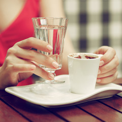 Female hands with traditional turkish coffee in street cafe. Close up.