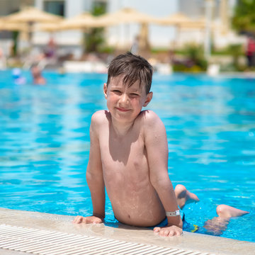 Happy smiling boy on side of swimming pool. He is looking at camera.
