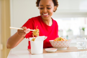 Beautiful young african american woman eating noodles using choopsticks