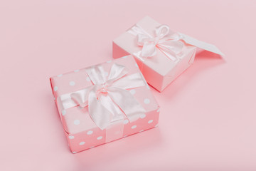 Gift box wrapped in pastel  paper with pink ribbon on pink surface. Top view  and  with copy space.
