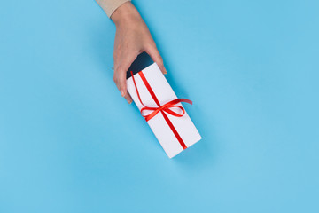 Womans hands holding gift or present box on blue pastel table. Flat lay  for birthday or New Year.