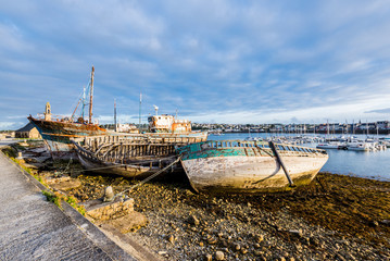 Old wooden fishing boats and yachts on the coast at sunset. Brittany, France