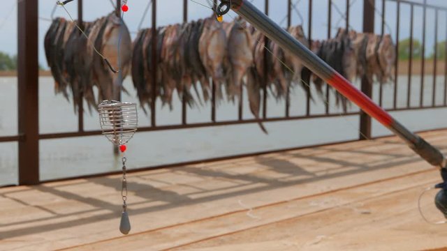 Feeder fishing gear on the background of dried fish hung in the sun. Pier near a small fishing village on the banks of the Volga River.