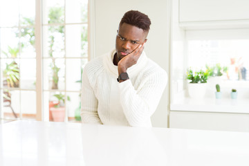 Handsome african american man on white table thinking looking tired and bored with depression...