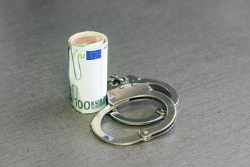 roll Euro money bills (banknotes) of 100 and 50 in handcuffs. Euro bills with handcuffs. Handcuffs...
