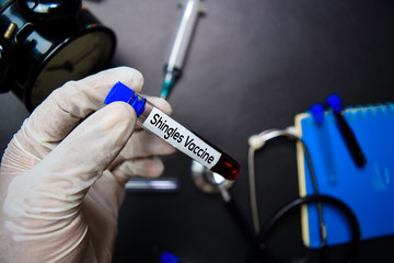 Shingle Vaccine text with blood sample. Top view isolated on black background. Healthcare/Medical...