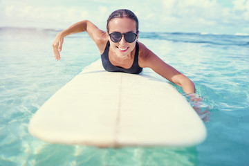 Portrait of surfer woman surfing having fun on Siargao Beach, Philippines. Female girl laughing on surfboard smiling happy living healthy lifestyle. - Powered by Adobe