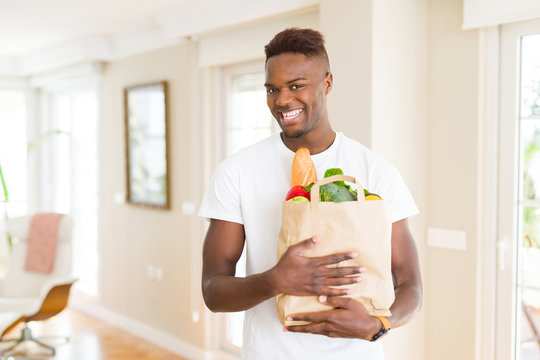 African american man holding paper bag full of groceries happy and smiling confident