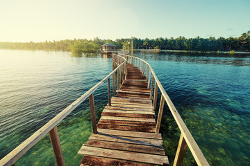 Fototapeta premium Beautiful landscape. Sunset on the seashore. Wooden bridge on the beach, Siargao Island, Philippines.