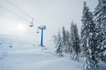 Ski lift with seats going over the mountain and paths from skies and snowboards.